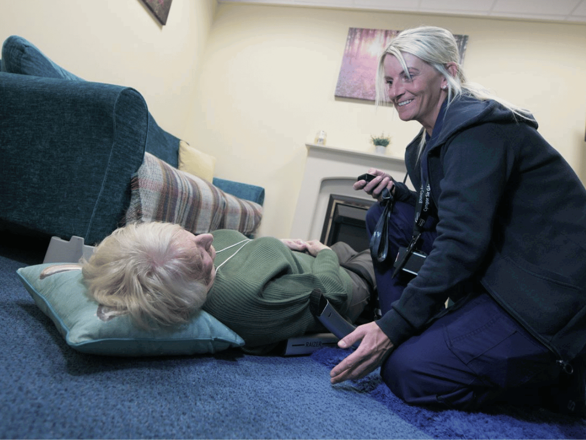 Menyw yn cael ei helpu o'r llawr gan ymatebydd