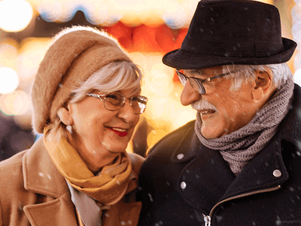 Dau berson y tu allan yn yr oerfel, yn gwisgo hetiau a sgarffiau yn y gaeaf