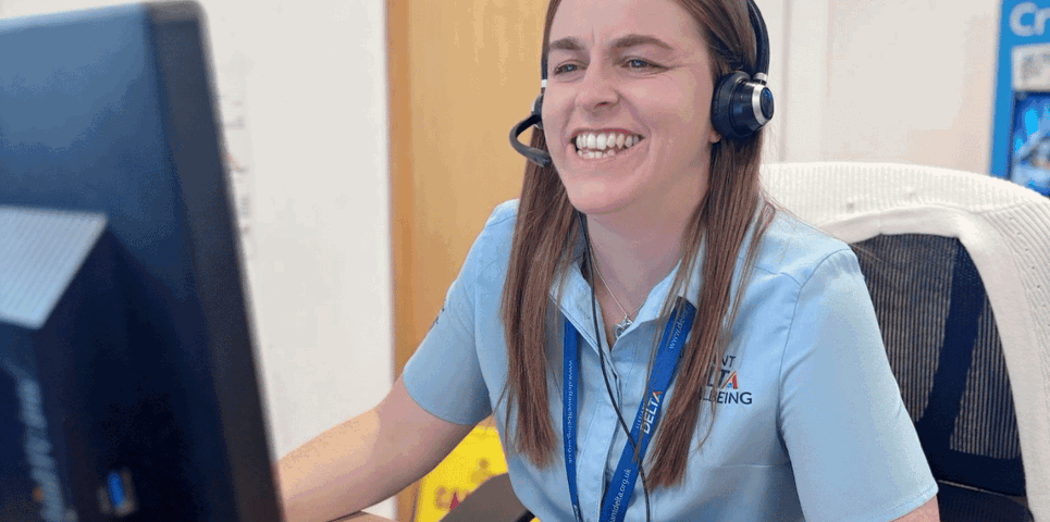 Cynghorydd Llesiant Delta yn eistedd wrth ddesg yn ateb galwadau brys